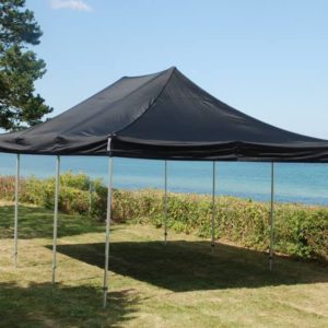 telt med sort teltdug opstillet på græsplæne ved hav