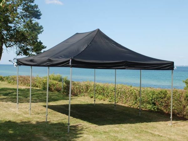 telt med sort teltdug opstillet på græsplæne ved hav